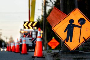 SEÑALETICA Lane closure on a busy road due to maintenance signs detour traffic temporary street work orange lighted arrow, barrels, and cones.
